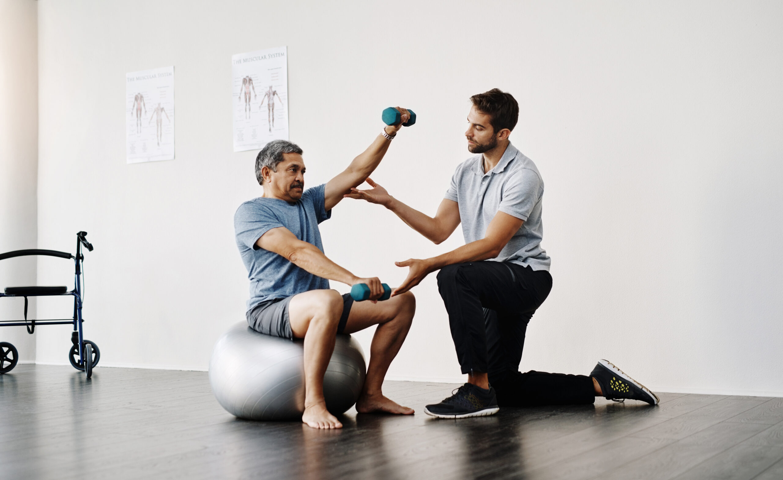 Slow and easy movements. Full length shot of a young male physiotherapist helping a mature male patient with movement exercises at a clinic.