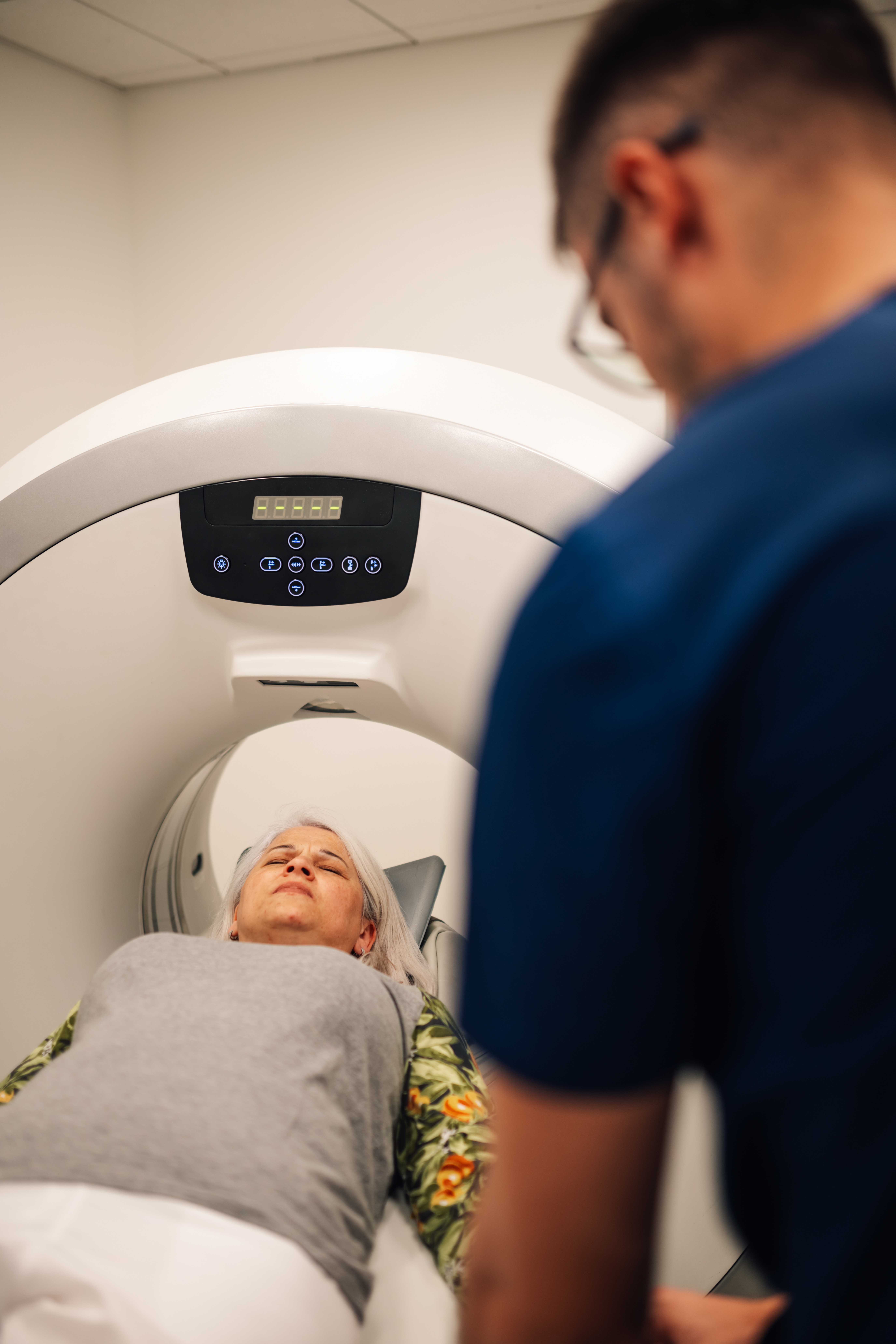 Patient undergoing CT scan procedure monitored by healthcare professional.