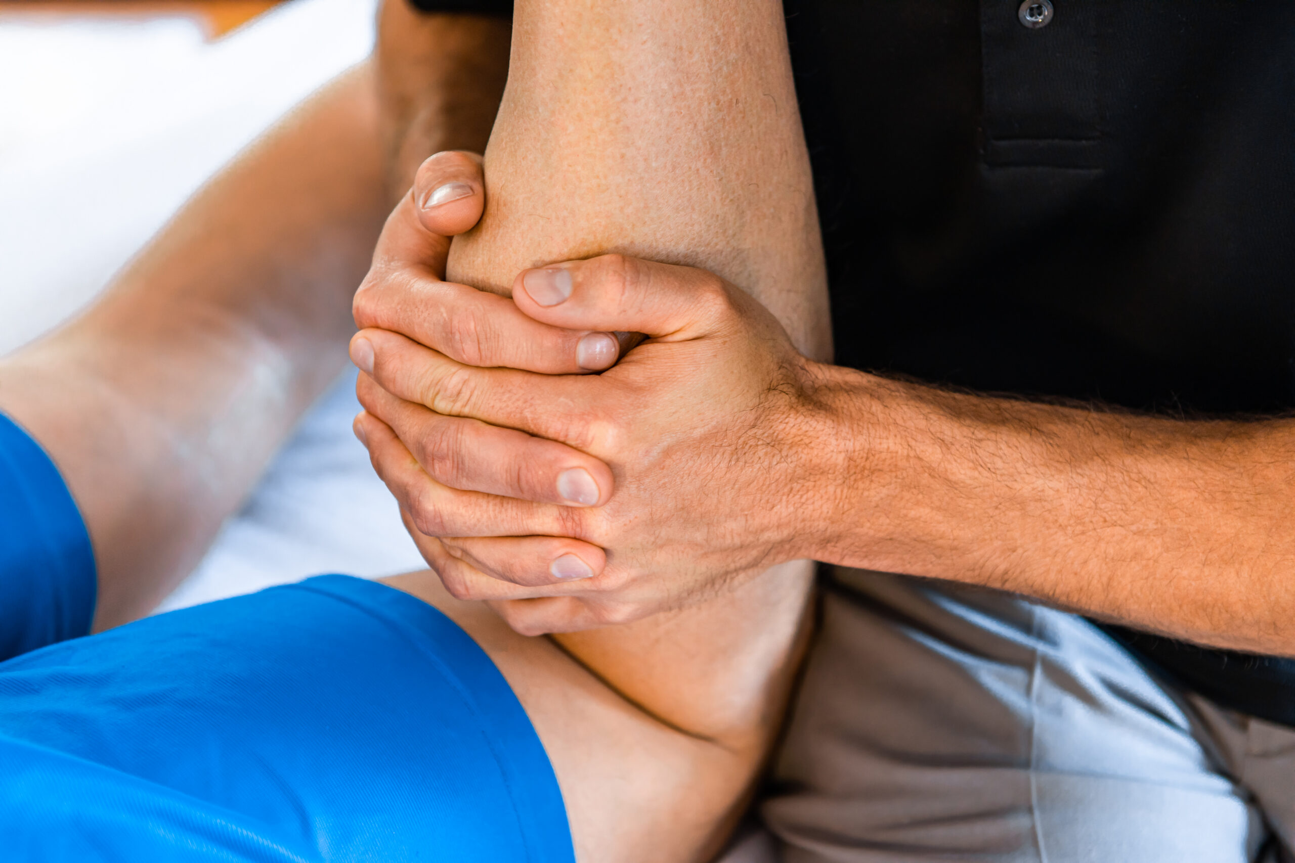 Sports Medicine Injury Care Evaluation Sports medicine provider evaluating a patient's lower leg during a musculoskeletal injury care examination.